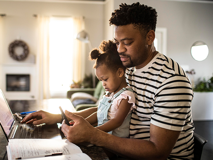 Man and girl sitting at desk in front of computer