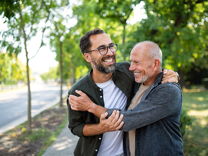 Elderly man young man hugging smiling