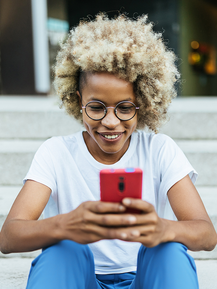 Girl in glasses smiling looking at phone