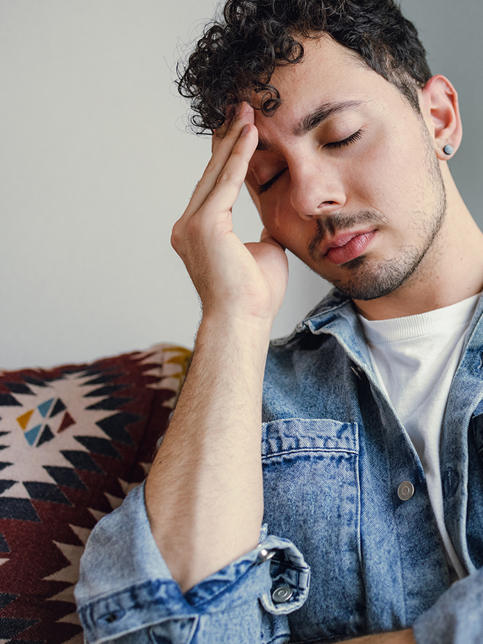 Man holding head with eyes closed