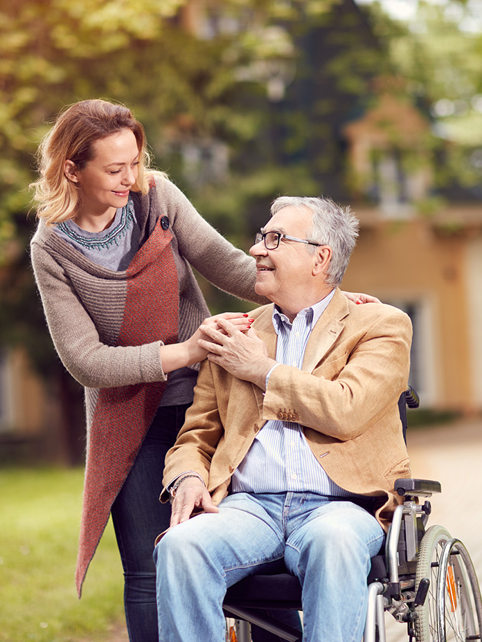 Man in wheelchair looking up at woman smiling