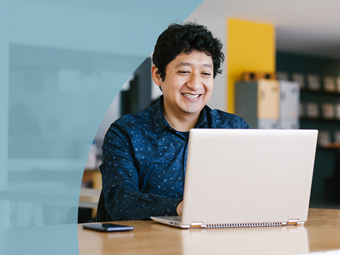 Boy in blue smiling at laptop