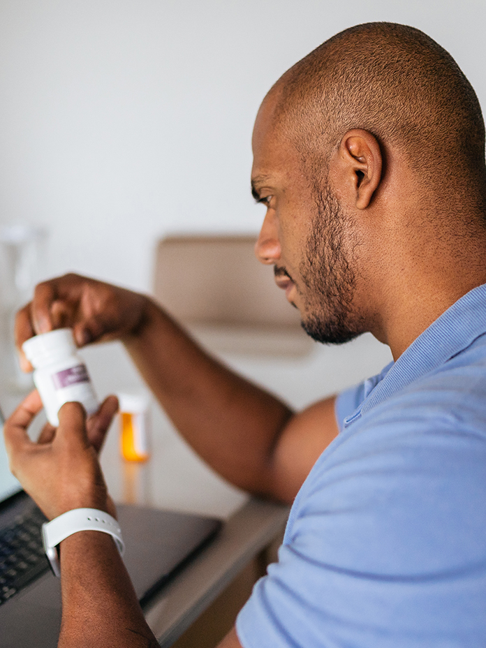 Man in blue reviewing medication bottle