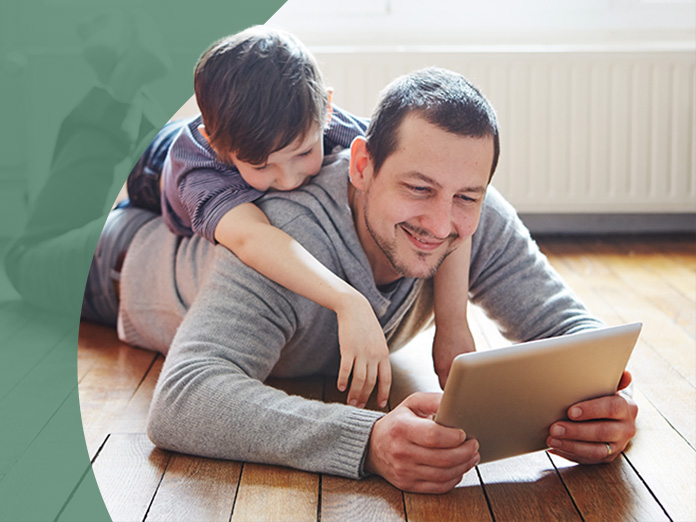 Boy on man's back looking at ipad