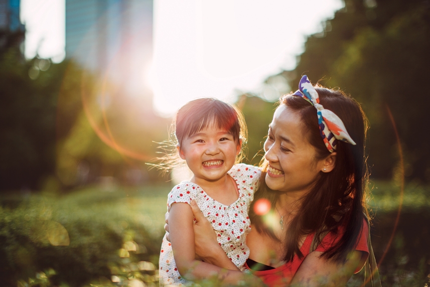 A woman and child smiling outside in a park