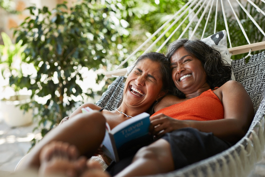 Two women laughing in a hammock
