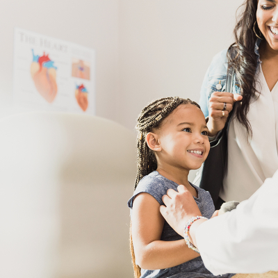 A doctor speaking to a child with her parent standing by