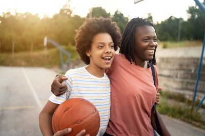 Two friends with their arms around each other, holding a basketball. 